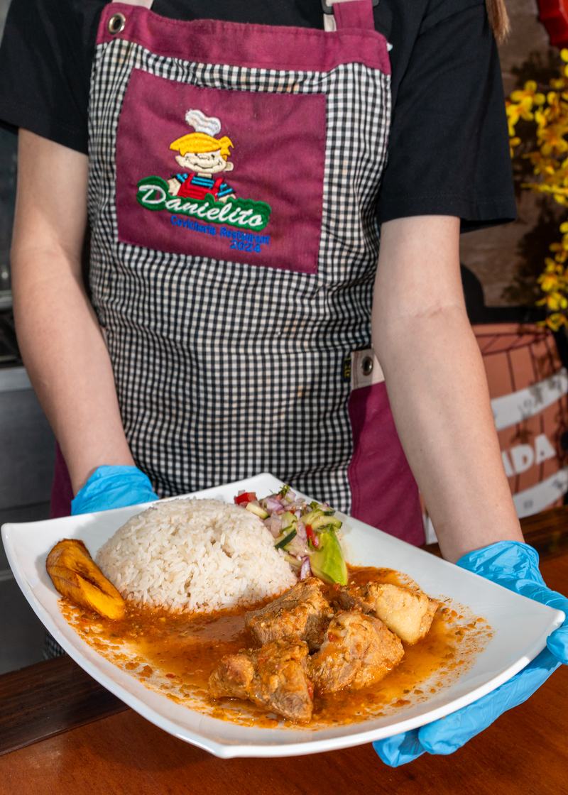 Personal de Danielito con delantal de la casa sirviendo un seco con arroz y maduro