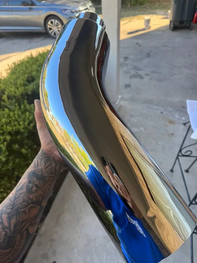 Hand holding a mirror-polished chrome exhaust elbow
