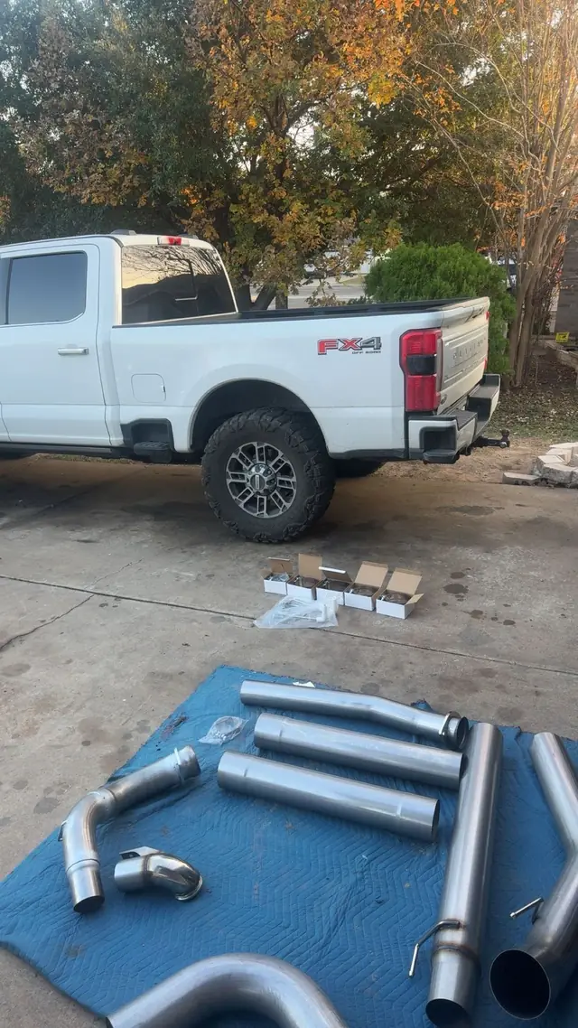 White Ford F-250 with a new exhaust system laid out on a mat