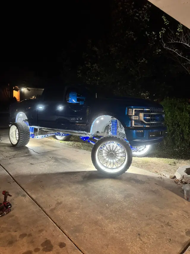 Lifted dark truck on chrome wheels, parked at night