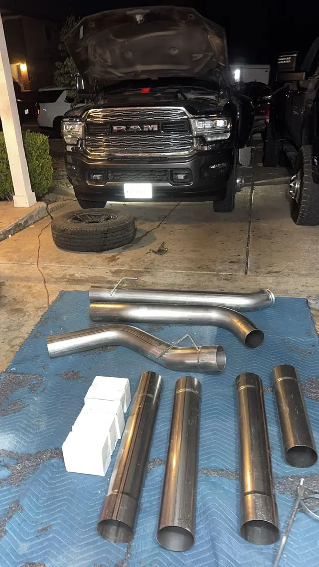 Ram pickup in the garage with new exhaust pipes laid out on a mat