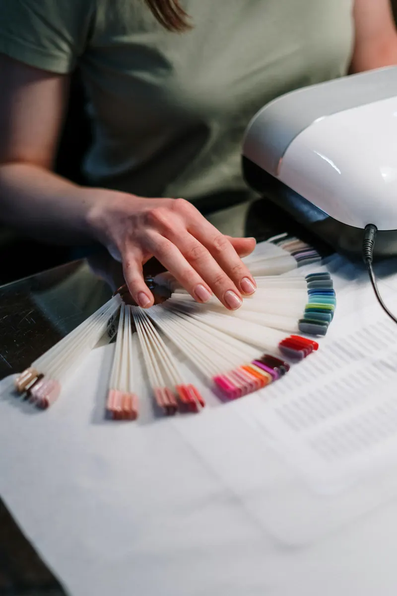 Muestrario de colores de esmalte en abanico junto a la lámpara de secado