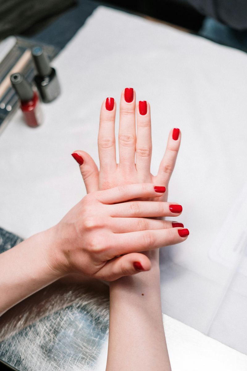 Manos con esmalte rojo brillante recién aplicado