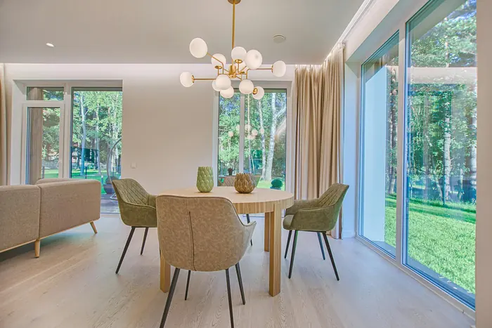 Comedor luminoso con mesa redonda de madera, sillas tapizadas y lámpara de globos dorada