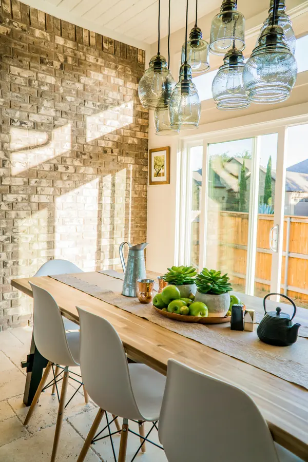 Mesa de comedor de madera maciza con sillas blancas y lámparas colgantes de vidrio