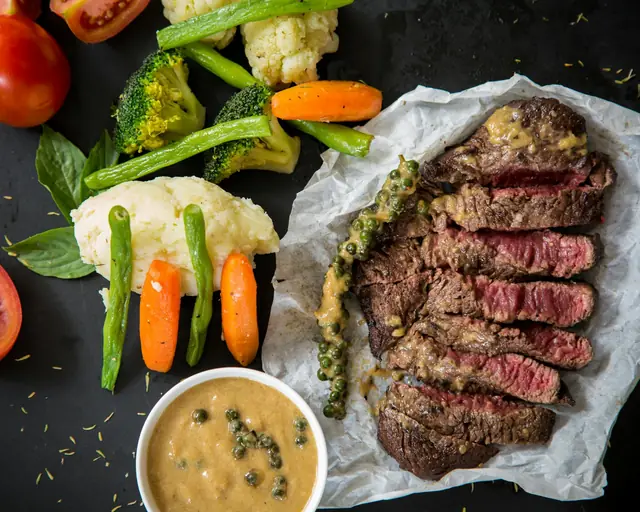 Carne en lonchas con salsa de hierbas, vegetales asados y salsa aparte