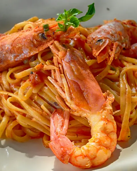 Langostinos enteros sobre pasta en salsa de tomate