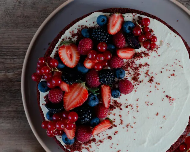 Postre cremoso decorado con fresas, frambuesas y arándanos